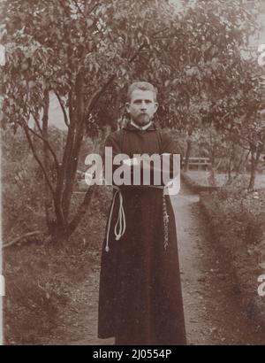 Ein junger gutaussehender römisch-katholischer Franziskanermönch posiert sehr gut für die Kamera in einem Obstgarten um 1890s Uhr. Quelle: Originalfoto. Stockfoto