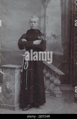 Ein junger gutaussehender römisch-katholischer Franziskanermönch posiert mit einem Blumenstrauß sehr gut für die Kamera bei 1890s. Quelle: Originalfoto. Stockfoto