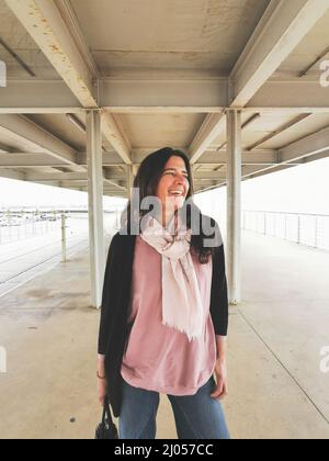 Frau mittleren Alters mit einer Tasche, die fröhlich und fröhlich im Freien posiert Stockfoto