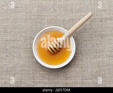 Schale mit Bio-Honig und Holzeimer Honig auf natürlichem Textil-Hintergrund, Draufsicht Stockfoto
