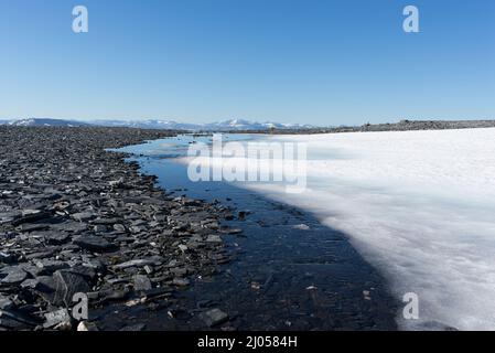 Wandern auf den Berg Blåhø in Trollheimen, Norwegen. Schmelzender Schnee auf dem Bergplateau. Stockfoto