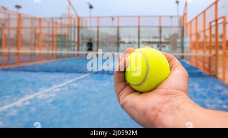 Monitor mit Paddle-Tennisball für den Padel-Unterricht an einen kaukasischen Schüler auf dem blauen Tennisplatz im Freien. Männlicher Spieler, der ein Spiel in der spielt Stockfoto