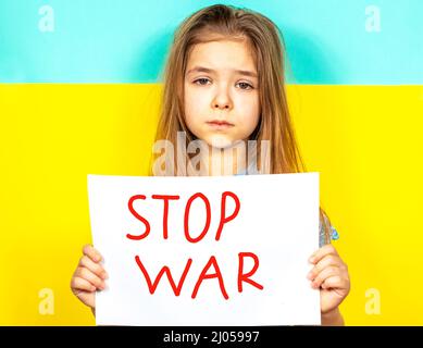 Das Mädchen hält vor dem Hintergrund der ukrainischen Flagge ein STOP-WAR-Plakat in den Händen. Platz für Beschriftungstext Stockfoto