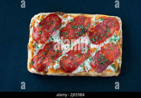 Salami Pizza al Taglio isoliert auf schwarzem BGD Stockfoto