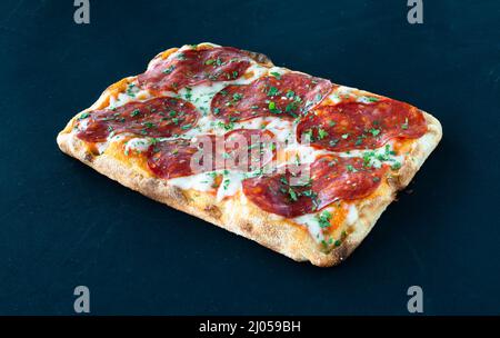 Salami Pizza al Taglio isoliert auf schwarzem BGD Stockfoto
