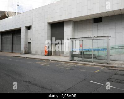 Arbeiter in hochsichtbarer PSA-Kleidung macht eine Pause in der Nähe einer Bushaltestelle auf der Stadtstraße. Birmingham Großbritannien Stockfoto