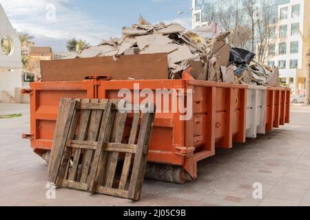 Riesiger Haufen auf Metall großer, überladener Müllcontainer, gefüllt mit Bauabfällen, Trockenbau und anderen Schutt in der Nähe einer Baustelle. Stockfoto