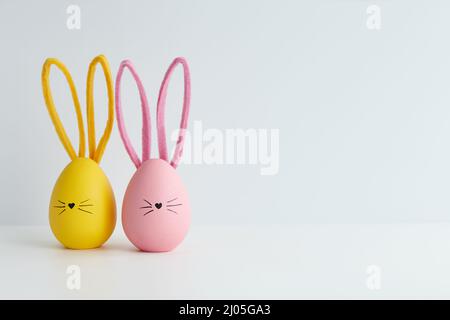 Rosa und gelbe Ostereier mit Hasengesichtern, Weihnachtsdekoration Stockfoto