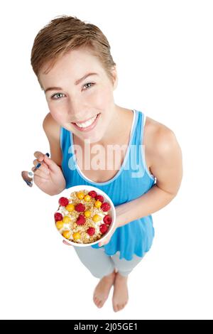 Gesund essen und glücklich sein. Studioporträt einer jungen Frau, die ein Müsli und Joghurt genießt. Stockfoto