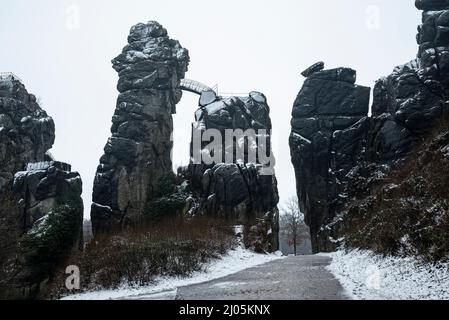 An einem bewölkten Wintertag ist die Felsformation Externsteine schneebedeckt, Teutoburger Wald, Deutschland Stockfoto