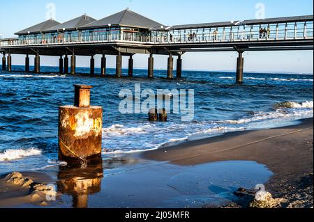 Ein rostiger Pol am ostseestrand vor dem Pier. Stockfoto