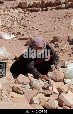 Eine einheimische Frau bricht in Petra Felsproben für Souvenirs Stockfoto