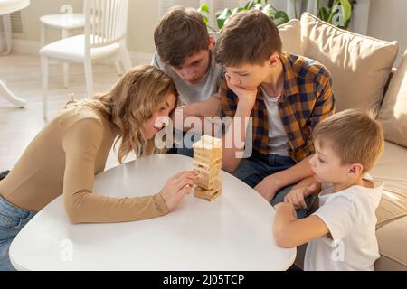 Familie, im Zimmer spielen ein Brettspiel aus rechteckigen Holzblöcken Stockfoto