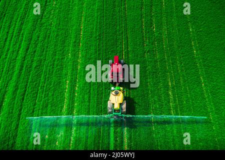 Luftaufnahme von landwirtschaftlichen Traktor Pflügen und Spritzen auf dem Feld. Stockfoto