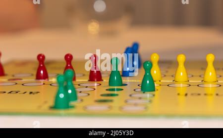 Nahaufnahme eines Brettspiels mit farbenfrohen Spielsteinen - konzentriere dich auf ein Spielstück mit reduziertem Tiefenfeld. Verschwommener Vordergrund und verschwommener Hintergrund Stockfoto