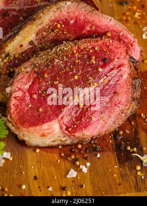 Appetitlich saftige Steaks aus Rindfleisch, Schweinefleisch in Gewürzen auf einem hölzernen Hintergrund paniert. Makrofotografie. Auf dem Foto befinden sich keine Personen. Das Konzept Stockfoto