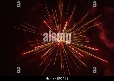 Knallrotes Feuerwerk, das am Nachthimmel Licht auf Rauch ausstrahlt Stockfoto