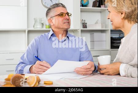 Frau und Mann diskutieren und Studium wichtigen Vertrag vor Unterzeichnung von Dokumenten. Stockfoto