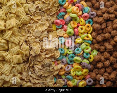 Verschiedene Vollkornfrühstücke - knusprige Pads, Müsli, fruchtige Maisringe und Schokoladenkugeln. Gesunde vegetarische und Babynahrung. Banner, Werbung. Stockfoto