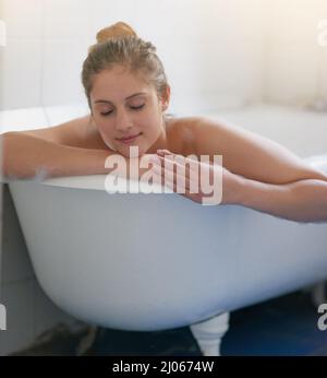 Die beste Art, sich nach einer langen Woche zu entspannen. Aufnahme einer schönen jungen Frau, die sich in der Badewanne entspannen kann. Stockfoto