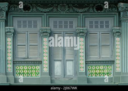 Grüne Straße Chinesisches Peranakan-Ladenhaus mit Holzlustern, Rokoko-Motiven, floralen Mosaikfliesen mit Taiji-Symbol und stilisiertem chinesischen Glückssymbol Stockfoto