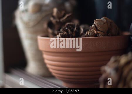 Cruse. Dinge auf dem Balkon. Alte Vase. Artikel im Regal. Trockene Kegel im Topf für Pflanzen. Stockfoto