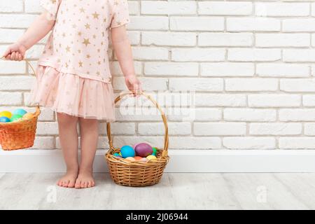 Unbekanntes Mädchen mit bunten Ostereiern in zwei Korbkörben Stockfoto