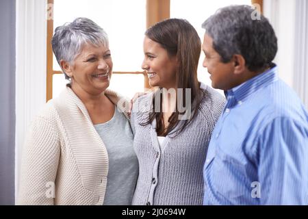 Es ist gut, zu Hause zu sein. Aufnahme eines älteren Paares, das mit seiner erwachsenen Tochter zu Hause steht. Stockfoto