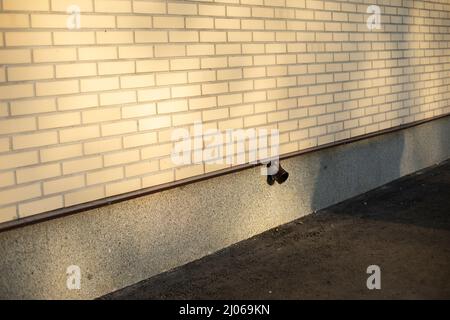 Aus einer Ziegelwand ragt ein Rohr heraus. Fassade des Gebäudes. Der weiße Ziegel wird diagonal geschossen. Stockfoto