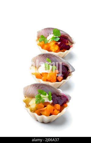 Heringsalat mit buntem Gemüse in kleinem Tartlet isoliert auf Weiß Stockfoto