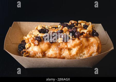 Rosinen Walnuss Frosted Zimtrolle Nahaufnahme auf schwarzem Hintergrund Stockfoto