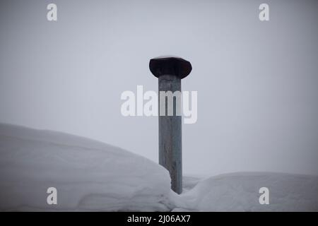 Kamin auf dem Dach. Wärmeableitung aus Edelstahl. Kamin aus dem Ofen. Schneebedecktes Wetter draußen. Stockfoto