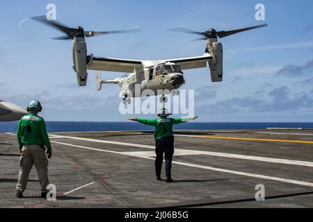 PHILIPPINE SEA (16. März 2022) Aviation Structural Mechanic (Safety Equipment) 2. Class Tyra Webb-Olam aus Detroit leitet einen CMV-22B Osprey, der den "Titanen" der Fleet Logistics Multi-Mission Squadron (VRM) 30 zugewiesen wurde, auf dem Flugdeck des Nimitz-Klasse-Flugzeugträgers USS Abraham Lincoln (CVN 72). Die Abraham Lincoln Strike Group befindet sich im geplanten Einsatzgebiet der US-Flotte für 7., um die Interoperabilität durch Allianzen und Partnerschaften zu verbessern und gleichzeitig als reaktionsfähige Truppe zur Unterstützung einer freien und offenen Region im Indo-Pazifik-Raum zu dienen. (USA Navy Foto von Mass Communication Stockfoto