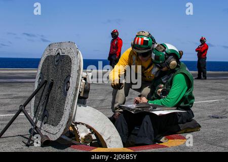 PHILIPPINE SEA (16. März 2022) LT. Caleb Derrington, links, aus Batesville, Ark., und Airman Cristina Rodriguez, aus Marlton, N.J., führen vor dem Start von Flugzeugen auf dem Flugdeck des Flugzeugträgers USS Abraham Lincoln (CVN 72) der Nimitz-Klasse Vorflugkontrollen durch. Die Abraham Lincoln Strike Group befindet sich im geplanten Einsatzgebiet der US-Flotte für 7., um die Interoperabilität durch Allianzen und Partnerschaften zu verbessern und gleichzeitig als reaktionsfähige Truppe zur Unterstützung einer freien und offenen Region im Indo-Pazifik-Raum zu dienen. (USA Navy Foto von Mass Communication Specialist Seaman Lehrling Julia Br Stockfoto