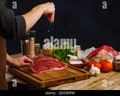 Zubereitung von Produkten aus einem ganzen Stück Fleisch - Schweinefleisch, Kalb, Rindfleisch von einem professionellen Koch. Das Konzept ist das Kochen von Gerichten aus Fleisch, Rezepte für mea Stockfoto