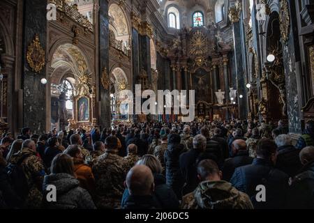 Lviv, Ukraine. 14. März 2022. Trauernde zollen drei gefallenen Soldaten ihren letzten Respekt. Die Trauernden zollen den drei gefallenen Soldaten, die beim russischen Luftangriff auf den Militärstützpunkt Javoriv am 13. März 2022 getötet wurden, ihren letzten Respekt. Lokale Behörden berichteten, dass 35 Menschen auf dem Stützpunkt, der sich in der Nähe der westlichen Grenze der Ukraine zu Polen befindet, getötet und 134 verletzt wurden. (Bild: © Laurel Chor/SOPA-Bilder über ZUMA Press Wire) Stockfoto