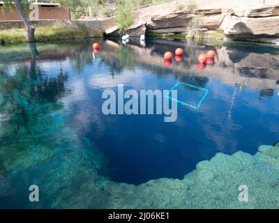 Klares blaues Wasser am Blue Hole in Santa Rosa, New Mexico, mit rot-weißen Tauchschwimmern, beliebt bei Schwimmern und Tauchern. Stockfoto