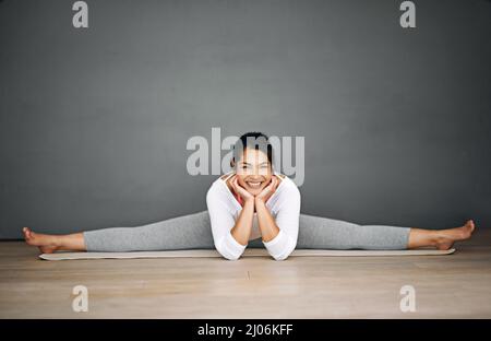 Yoga ist der beste Weg, um den Tag zu beginnen. Porträt einer attraktiven jungen Frau, die die Splits in ihrer Yoga-Routine macht. Stockfoto