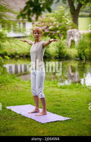 Meditieren in der Natur. Aufnahme einer Frau, die im Park Yoga macht. Stockfoto