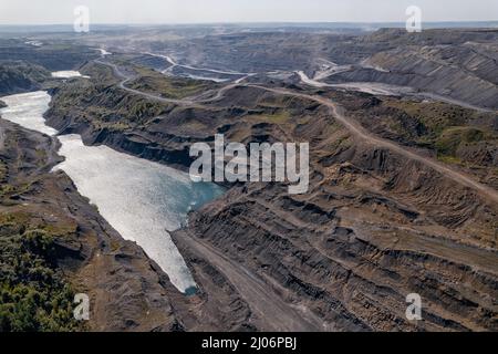 Pumpen von Wasser aus dem Boden der Tagebaumine für die Gewinnung von Kohle, Luftdrohne Draufsicht. Stockfoto