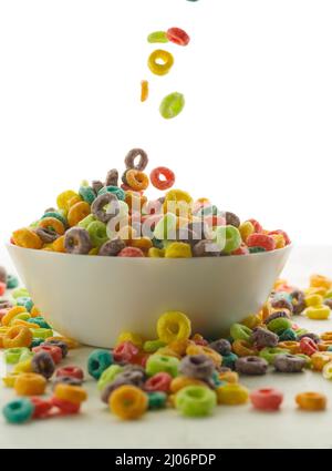 Cerealien knusprige, mehrfarbige Ringe in einer Schüssel und in der Nähe auf weißem Hintergrund. Nahaufnahme. Müsli schnelles Frühstück, Nährstoffe, Vitamine, gesundes Livestyl Stockfoto