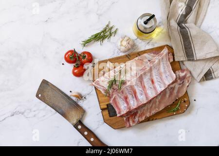 Rohes Kalbsbriketts Fleisch mit Gemüse und Gewürzen auf kurzen Rippen zum Kochen auf Marmorplatte. Draufsicht, flach liegend. Stockfoto