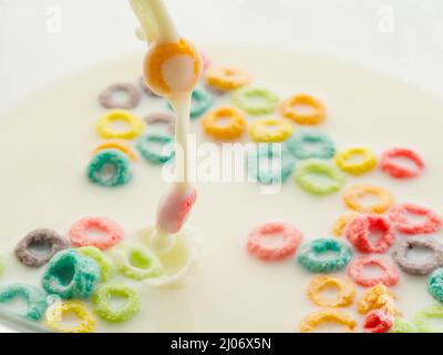 Cerealien, mehrfarbige Obstringe mit Milch - ein schnelles Müsli-Frühstück. Nützliche vegetarische, Kinder-, Diät-Essen. Hotel, Café, Hausmannskost, sup Stockfoto