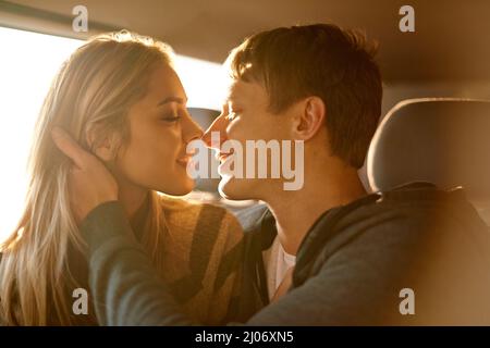 Süße Vorfreude. Aufnahme eines liebevollen jungen Paares, das sich in einem Auto küssen wird. Stockfoto