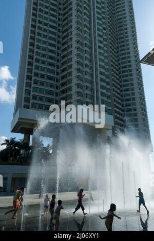 Kinder spielen im Stadttor-Brunnen mit dem Hochhaus Tung Chung Crescent Block 5 im Hintergrund, Tung Chung, Lantau Island, Hong Kong, 2007 Stockfoto