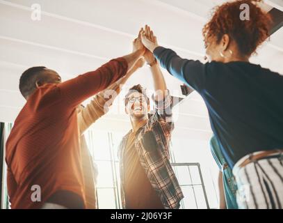 Zusammenarbeit und Innovation. Aufnahme kreativer Mitarbeiter, die sich im Büro gegenseitig einen High-Five geben. Stockfoto