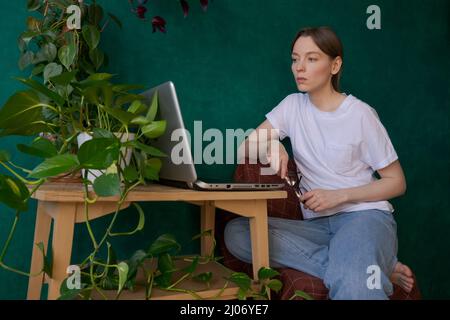 Elektronische Dokumente. Konzentrierte junge Kleinunternehmen Frau Floristin Besitzer mit Laptop auf dem Desktop im Studio. Floral Arranger Designer im Internet recherchieren Kundensuche Trends online Stockfoto