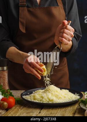 Chef reibt Käse Mozzarella, für die Vorbereitung von Salat, Pizza .Freezing in Bewegung.Konzept der Küche und Rezept Bücher.kulinarische Hintergrund Stockfoto