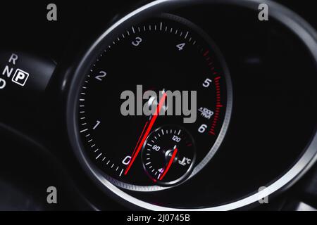 Auto-Tachometer mit glühenden roten Indikatoren Nahaufnahme, von Luxus-Armaturenbrett in Sportwagen Stockfoto