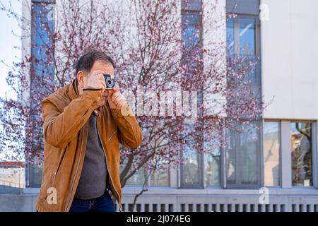 Älterer Mann, der mit seiner alten Filmkamera fotografiert. Stockfoto